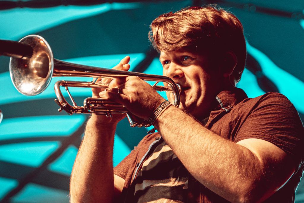 Down to the Nub, Bristol Dub Catalyst trumpeter Andy playing live at Mucky Weekender 2026 in Winchester, close-up under teal stage lighting
